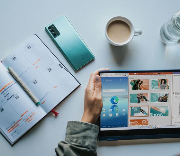 person using Windows 11 computer beside white ceramic mug on white table