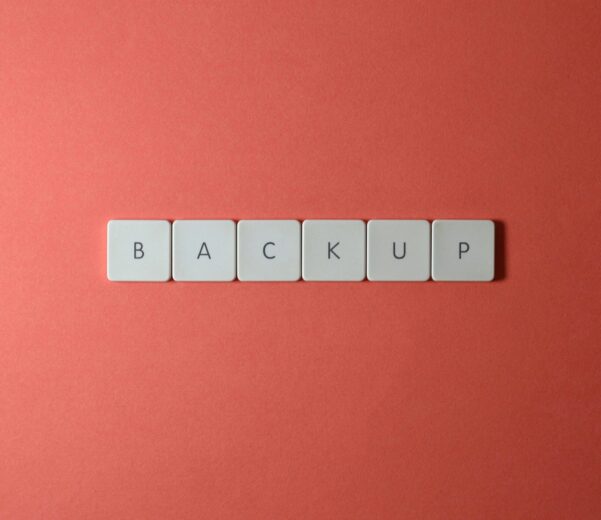 Free Close-up of keyboard keys spelling 'BACKUP' placed on a coral-colored surface. Stock Photo